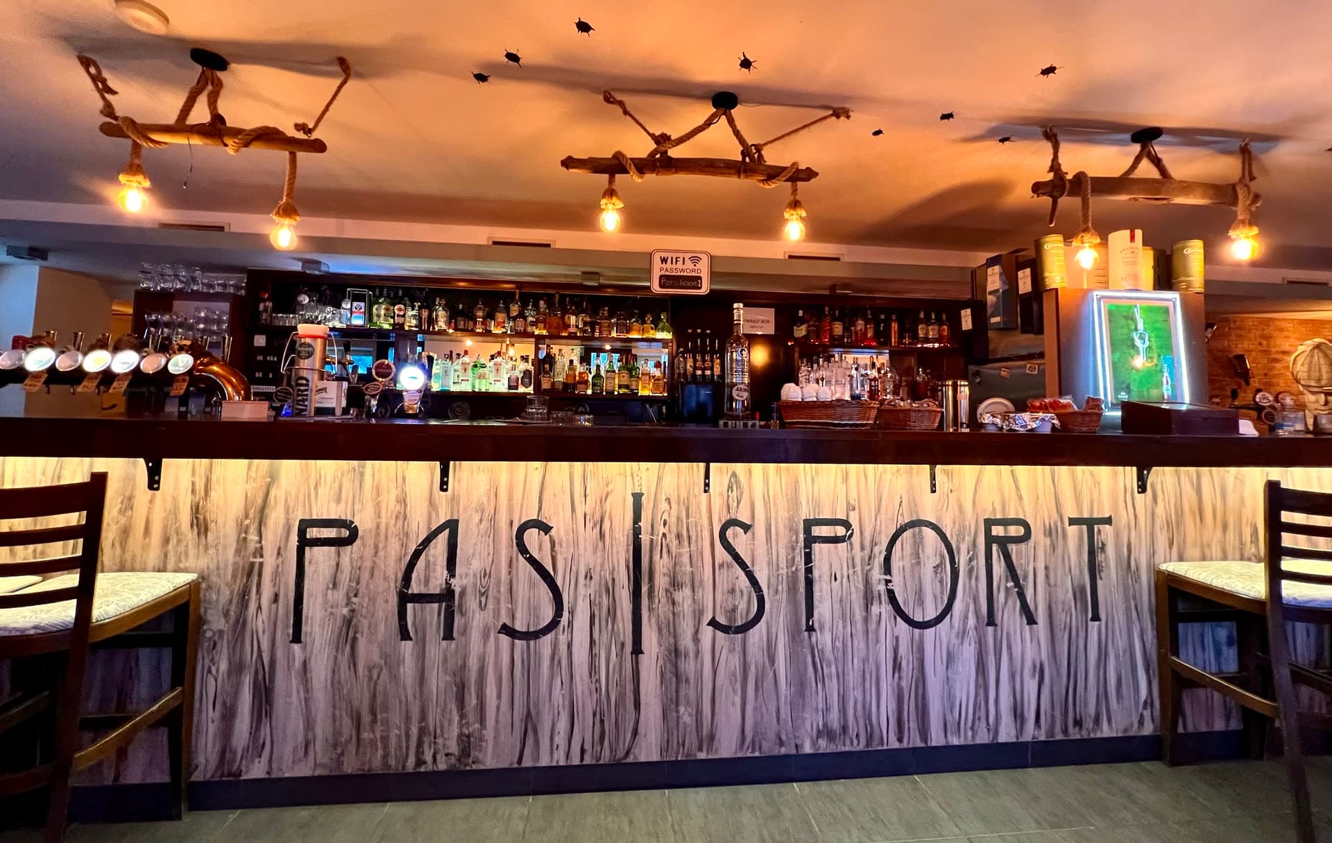 A Passport Pub pultja a kézzel festett PAS|SPORT felirattal és kötélre függesztett lámpákkal